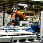Robot industriel orange intégré à une ligne de manutention de panneaux