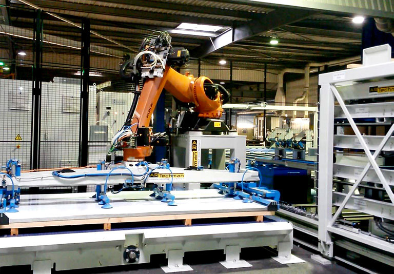 Robot industriel orange intégré à une ligne de manutention de panneaux
