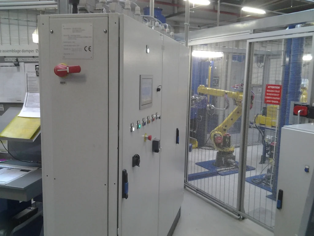Armoires électriques devant une cellule robotisée en atelier de production