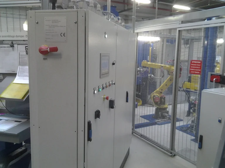 Armoires électriques devant une cellule robotisée en atelier de production