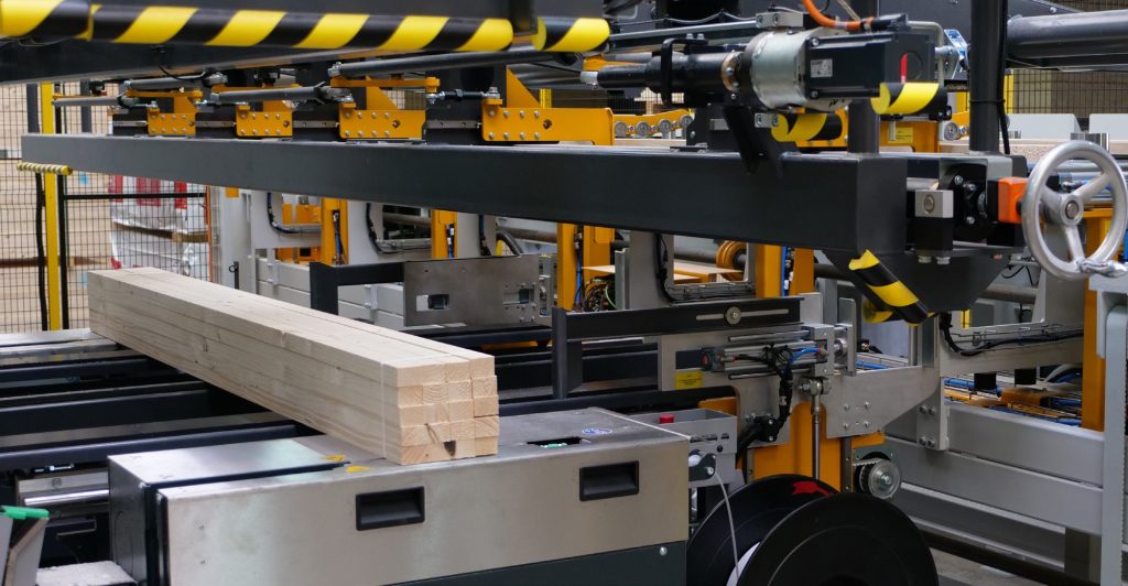 Mise en botte et cerclage de bois en sortie de ligne de rabotage, France Poutres